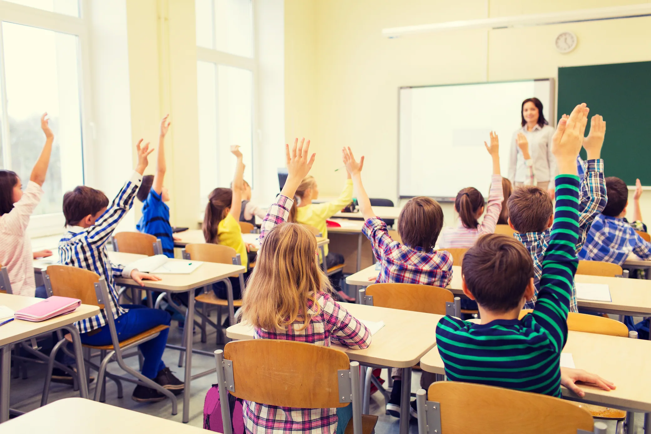 Schoolchildren raising their hands in a classroom