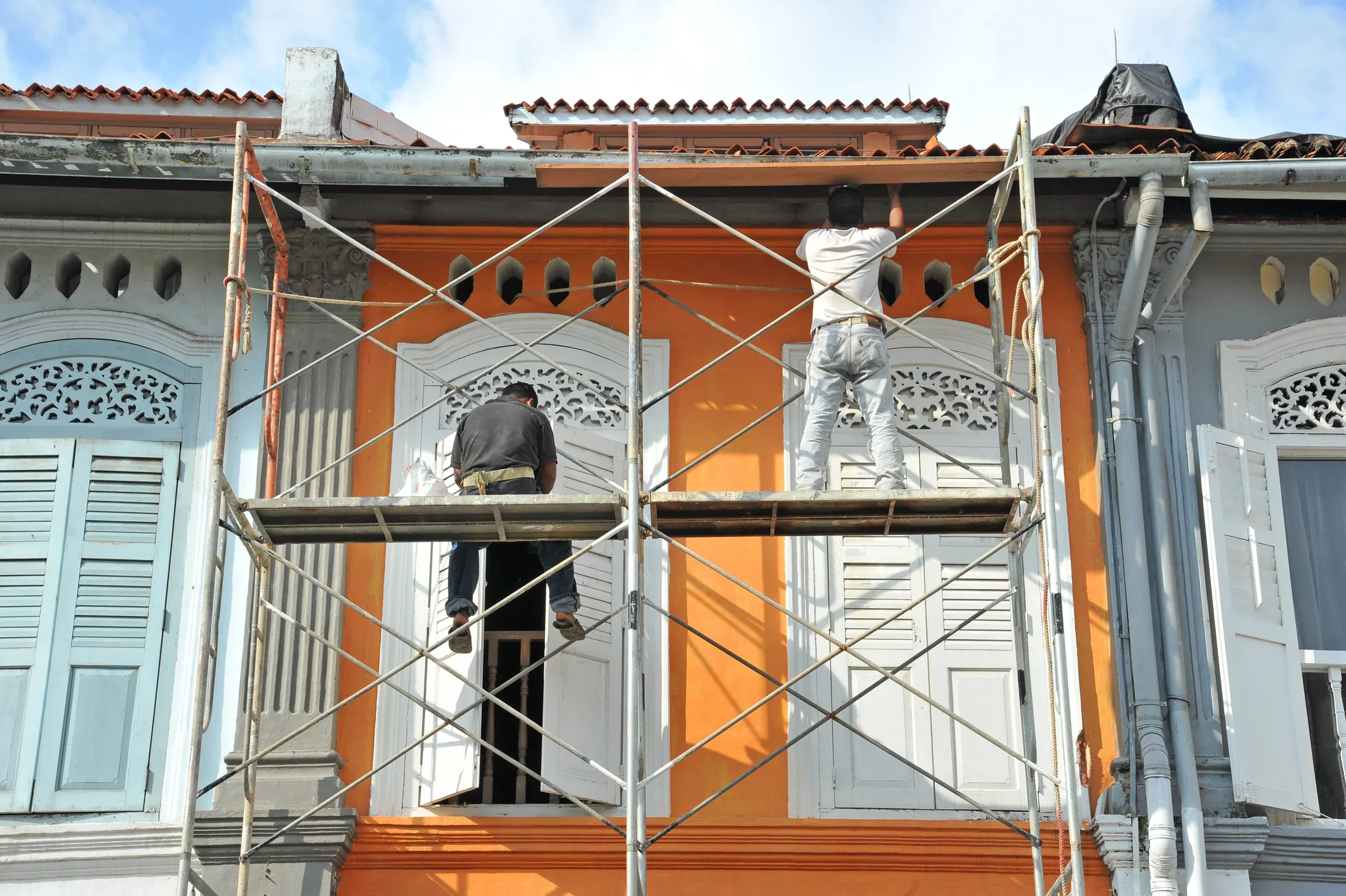 Workers on scaffolding renovating the façade of a terraced house
